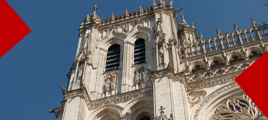 Vue en contre-plongée des tours gothiques de la cathédrale d'Amiens, avec sa façade ornée de sculptures et de gargouilles sous un ciel bleu clair