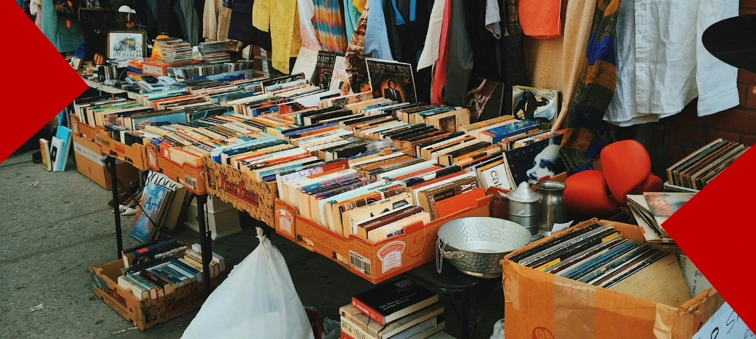 Étalage de livres d'occasion, vinyles et objets anciens sur des tables lors d'une réderie en plein air.