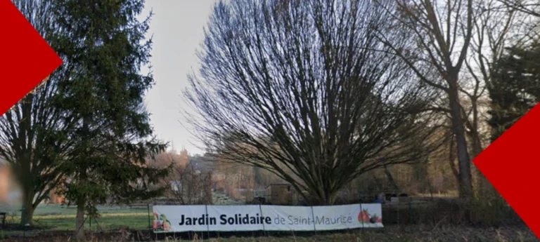 Vue d'un espace vert avec de grands arbres en arrière-plan. Au premier plan, une banderole est accrochée à une clôture, avec l'inscription « Jardin Solidaire de Saint-Maurice » accompagnée d'illustrations de fruits et légumes.