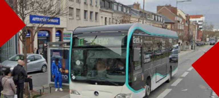 Un bus moderne blanc et turquoise du réseau Ametis circulant dans une rue urbaine à Amiens. Le bus affiche la destination « L1 Saleux ». À l'arrière-plan, on aperçoit un arrêt de bus avec quelques passagers qui attendent, des bâtiments de ville et une enseigne d'auto-école bleue.