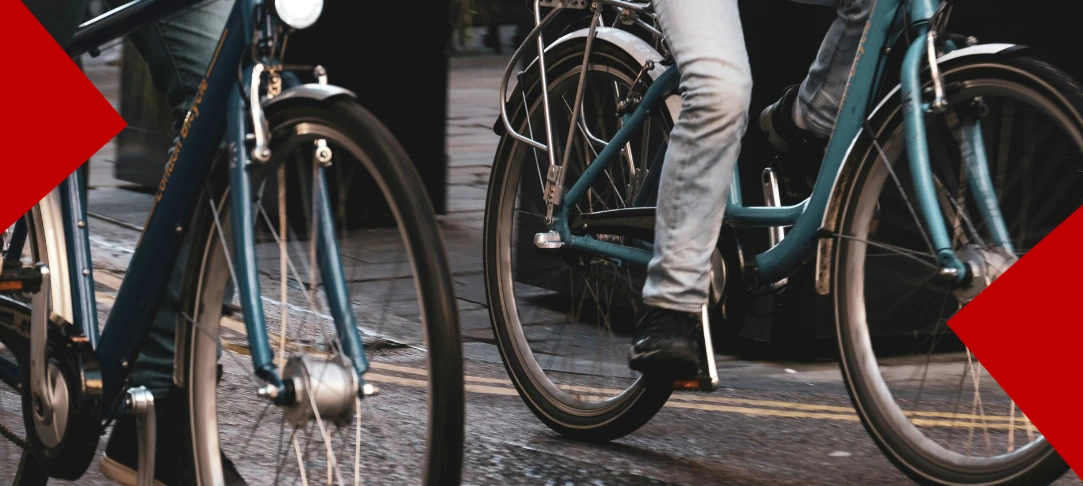 Gros plan sur les roues et le bas du cadre de deux vélos de ville circulant sur une rue pavée.