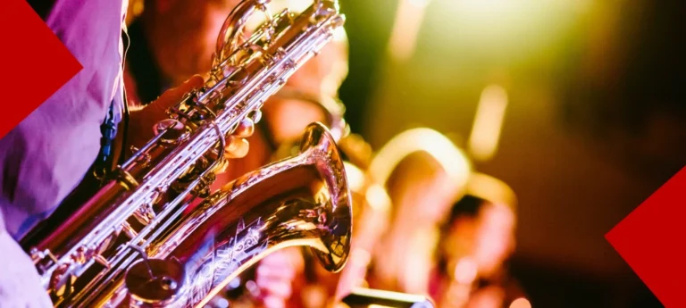 Gros plan sur un saxophoniste jouant dans un orchestre de cuivres sous des projecteurs chauds lors d'un concert de jazz.