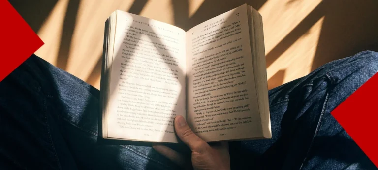 Vue subjective d'une personne lisant un livre, un rayon de soleil éclairant les pages ouvertes sur les genoux.