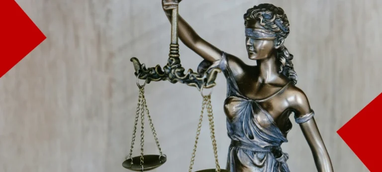 Statuette en bronze de la Justice aveugle tenant une balance, sur un fond texturé clair avec des formes géométriques rouges dans les angles.